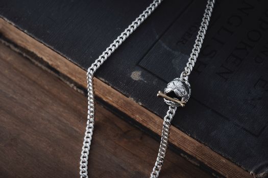 A stylish silver chain necklace elegantly placed on a rustic book, showcasing intricate jewelry design.