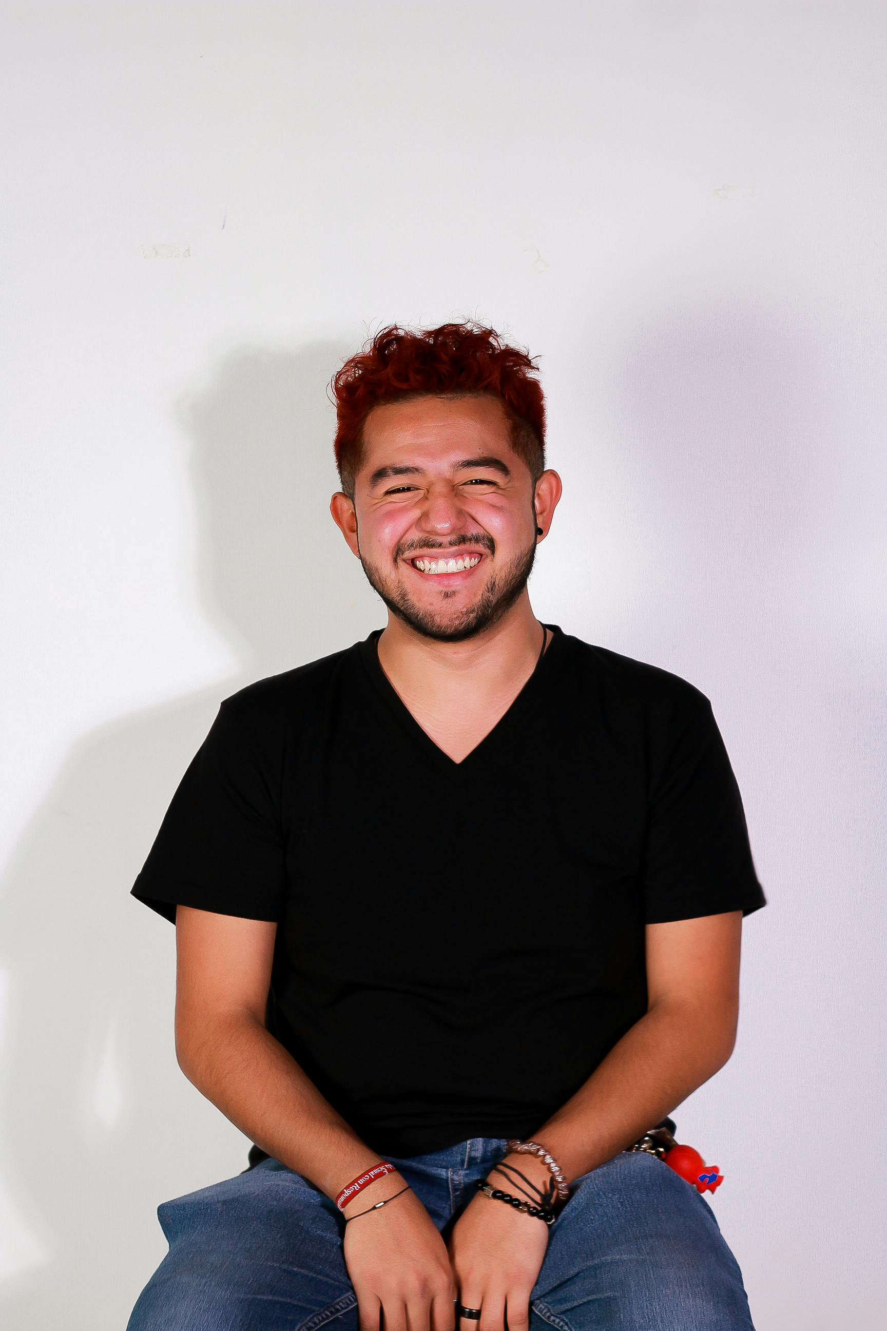 Cheerful young man with red hair smiling in a studio setting, exuding positivity.