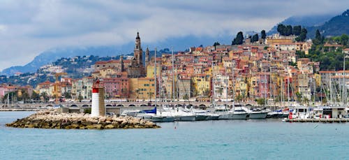 Houses Near With Sea With Sailboats and Lighthouse during Daytime