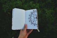 Person Holding Open Book with Floral Drawing
