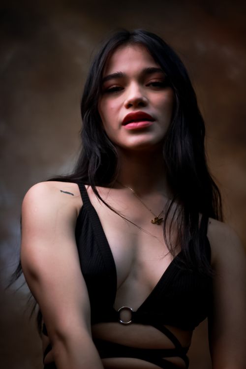 Free Striking portrait of a woman in a stylish black top with long dark hair, exuding confidence and elegance. Stock Photo