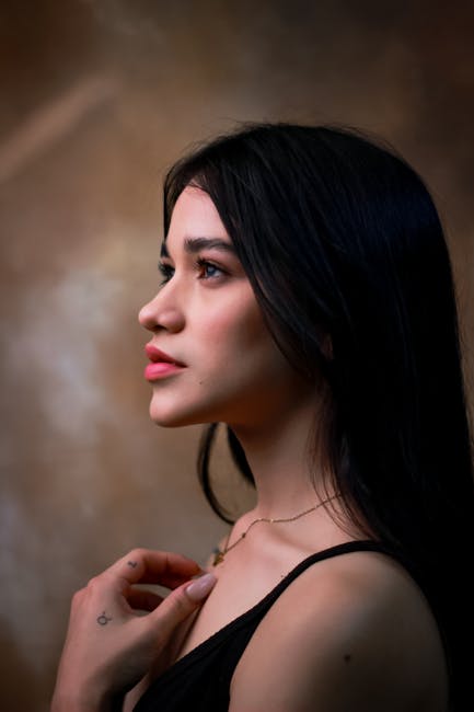 Profile portrait of a young woman with long dark hair in a studio setting, exuding elegance.