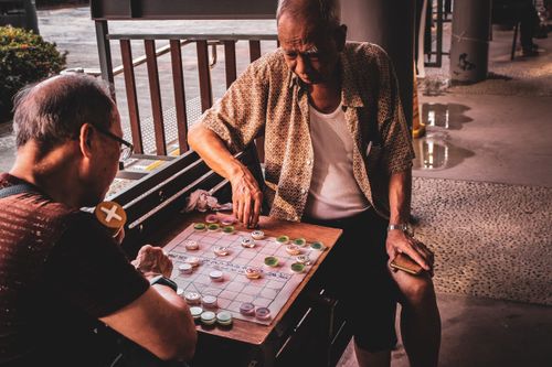 Free Two senior men enjoy an outdoor game of Chinese Checkers in Hong Kong. Stock Photo