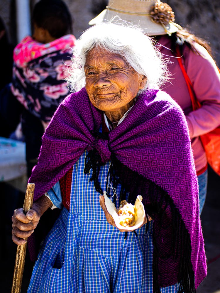 Elderly Woman With A Walking Stick And Food In Hand