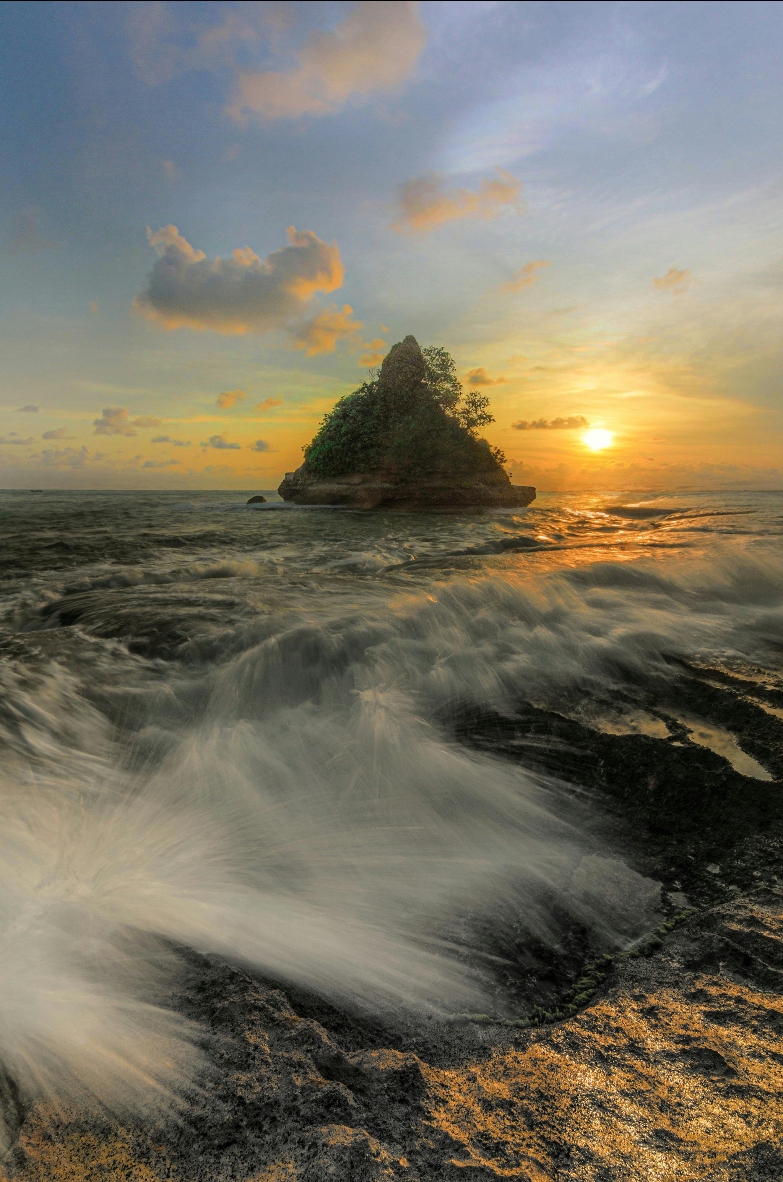 Stunning seascape of wild waves crashing against rocks at sunset in Java, Indonesia.