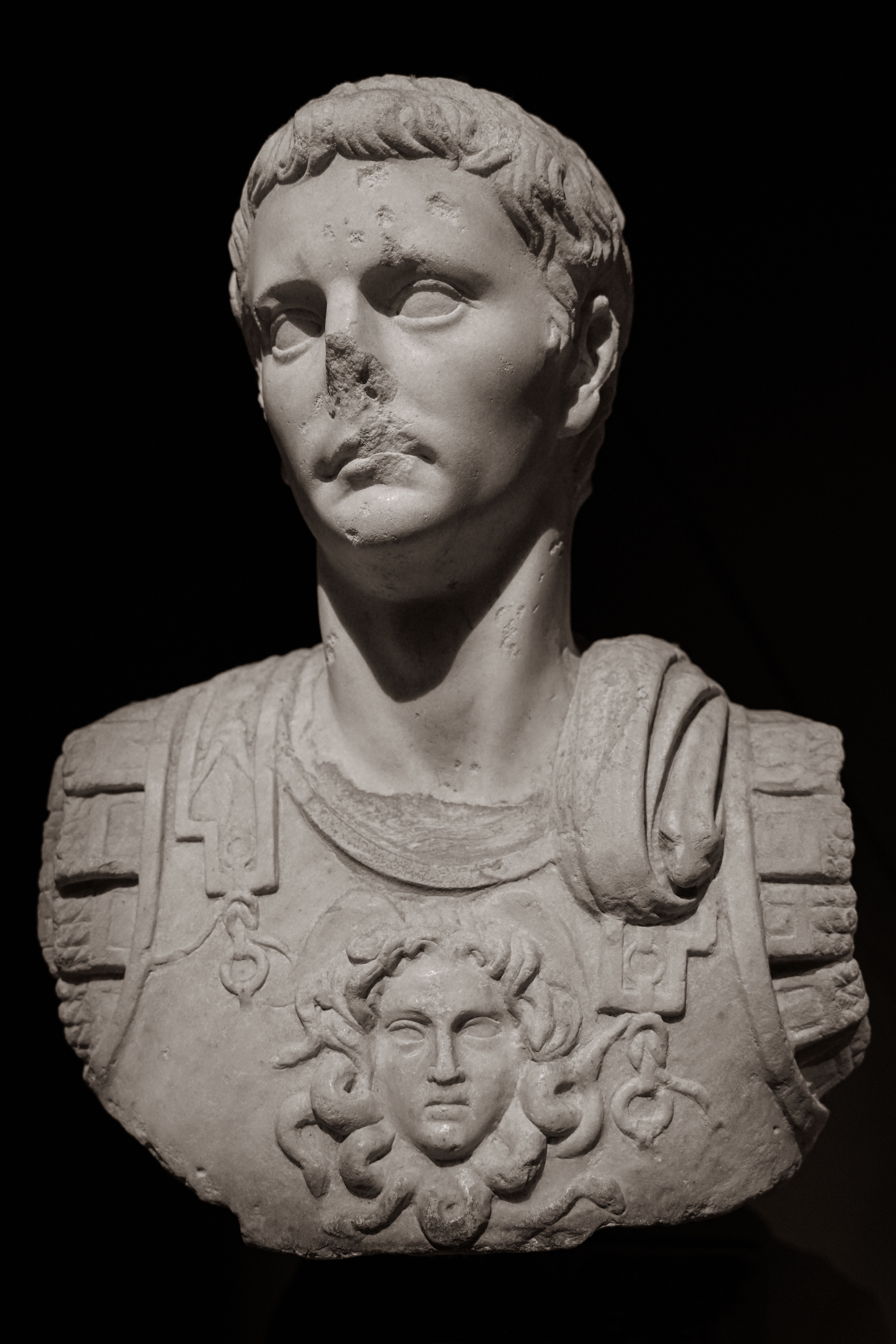Detailed photo of a damaged marble Roman bust in a museum setting.