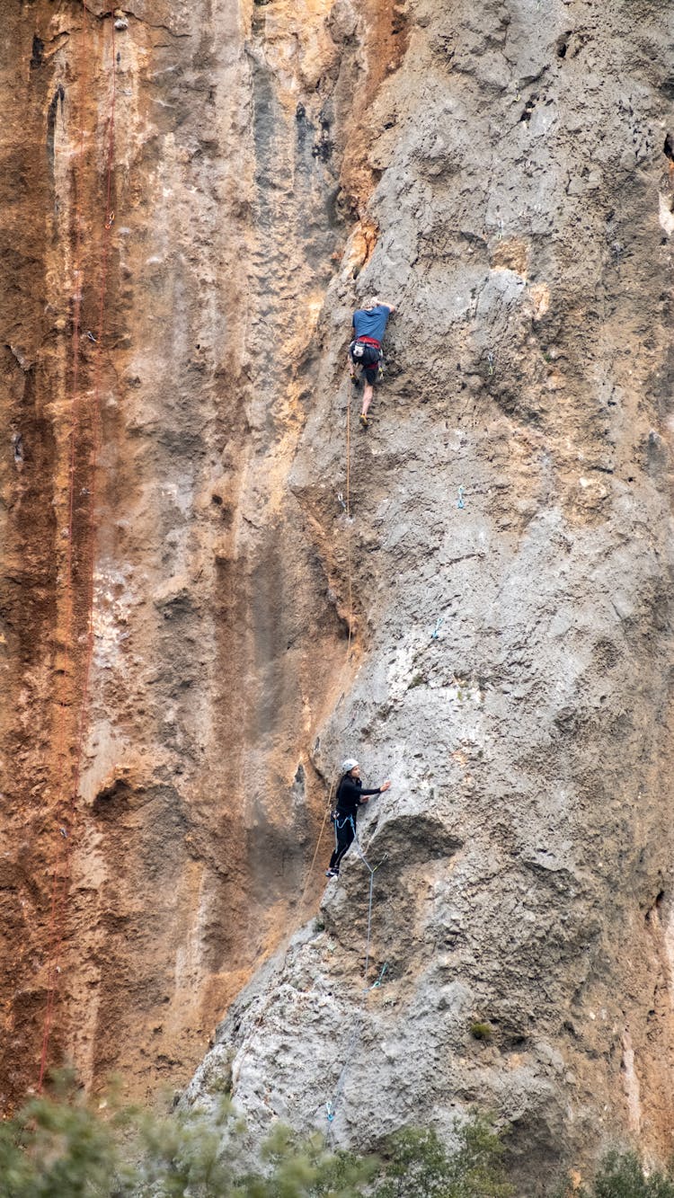 Couple Climbing A Stone Wall