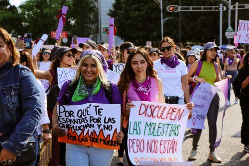Free Women marching with colorful protest signs during a vibrant feminist demonstration. Stock Photo