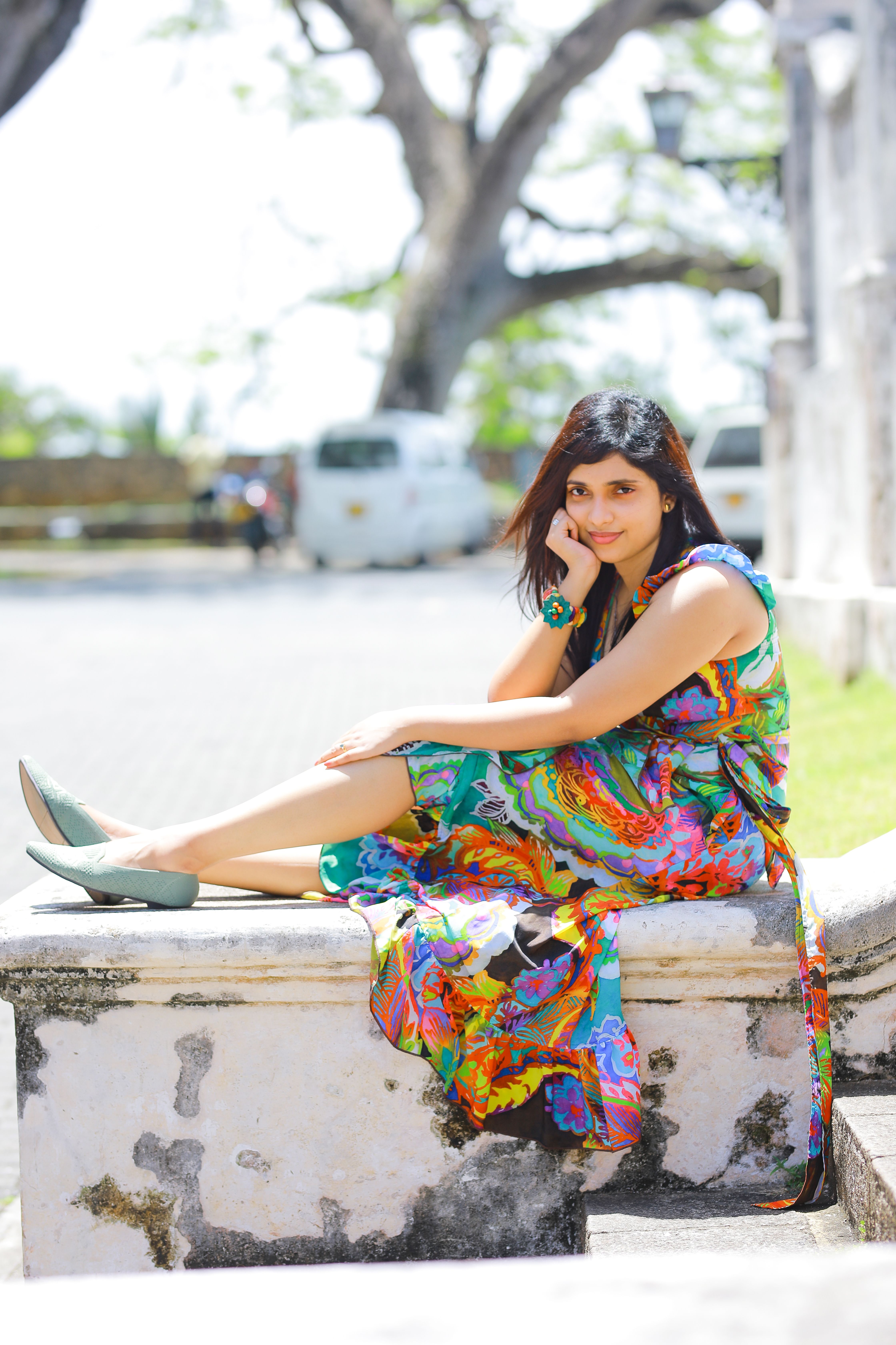A woman in a colorful dress posing outdoors, exuding vibrant style and elegance.