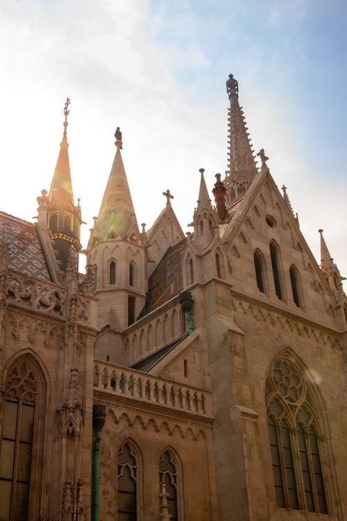 Free A beautiful low-angle view of the Matthias Church facade in Budapest, capturing the intricate Gothic architecture in sunlight. Stock Photo