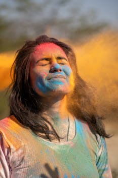 A young woman enjoying Holi, the festival of colors, with colorful powder on her face and a joyous expression.