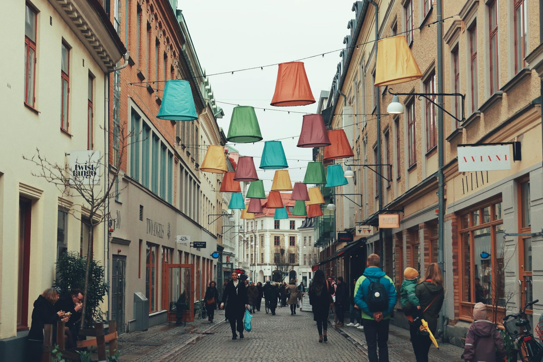 A street with people walking down it and colorful lights hanging from the ceiling