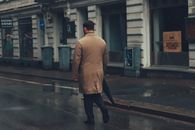 A man walks on a rainy street in Gothenburg, Sweden, holding a folded umbrella.