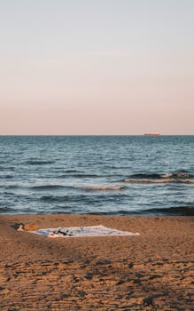 Serene view of a sandy beach with a blanket during sunset in Castellón de la Plana, Spain.