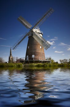 在宁静的河畔，迷人的风车和教堂倒映在蔚蓝的天空下