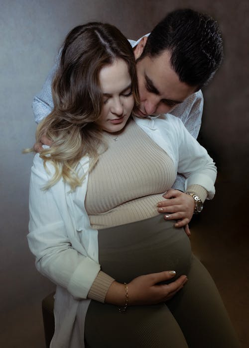 Man and Pregnant Woman Hugging and Touching the Womans Stomach 