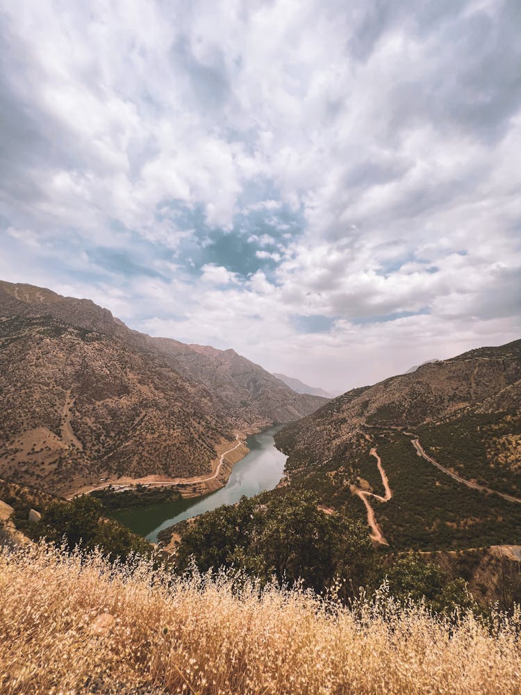 River Between Mountains Under Cloudy Sky