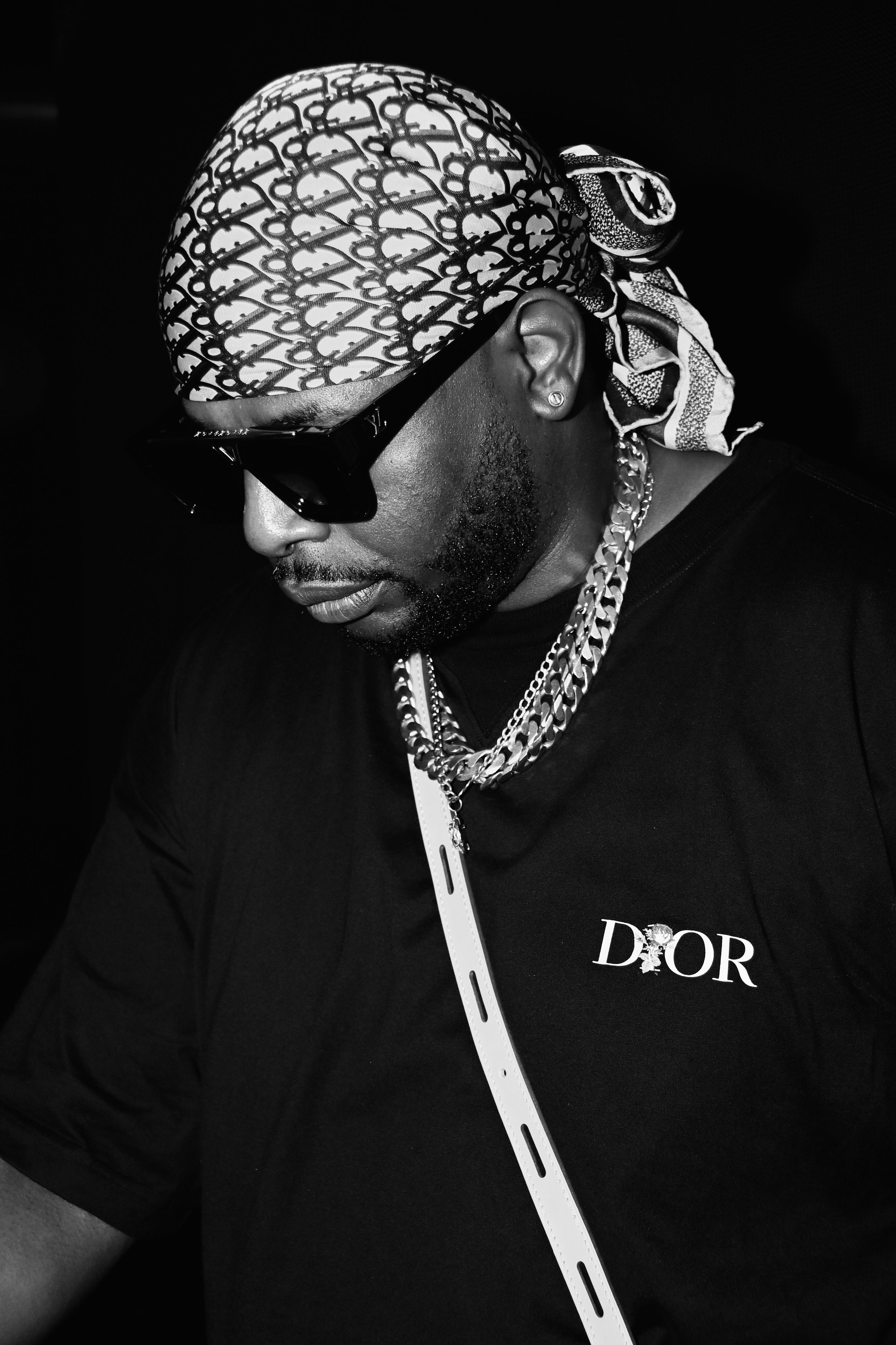 Black and white image of a man wearing sunglasses and a bandana, embodying urban style.