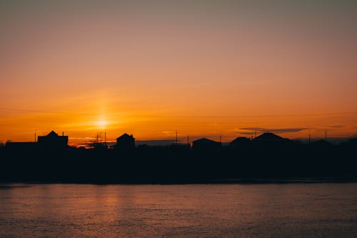 Buildings Silhouette on Horizon near Water on Sunset