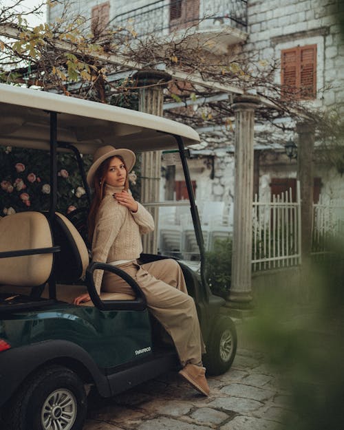 Woman in a Hat and Turtleneck Sitting in a Golf Cart