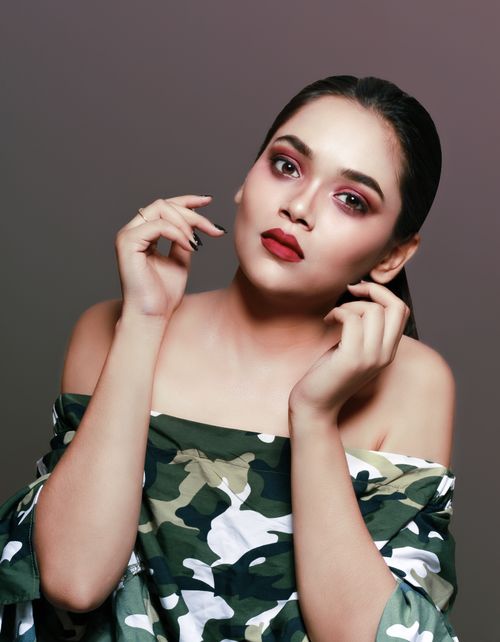 Free Elegant portrait of a woman in camouflage attire with striking makeup and black hair. Stock Photo