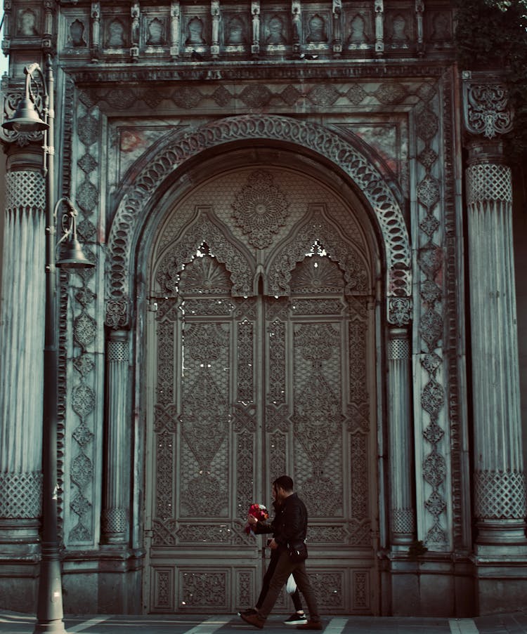 Couple With Flower Bouquet Walking By The Church Door 