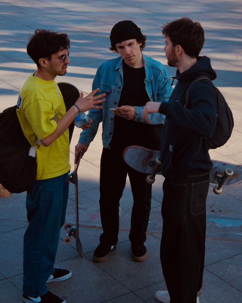 Free Three young men with skateboards chatting in an outdoor skatepark. Stock Photo