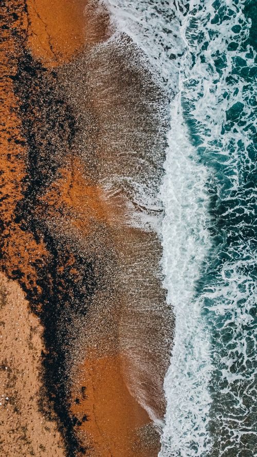 Free Stunning aerial view of ocean waves crashing on the sandy shore of Oceanside, CA, showcasing vibrant colors and textures. Stock Photo