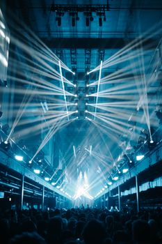 Dynamic nightclub scene featuring dazzling light beams illuminating a vibrant concert crowd.