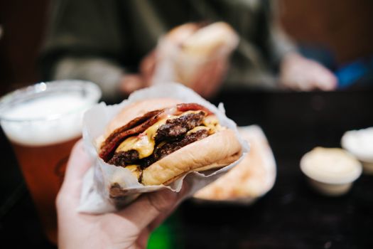 Appetizing cheeseburger with crispy bacon and pint of beer, perfect meal setting.