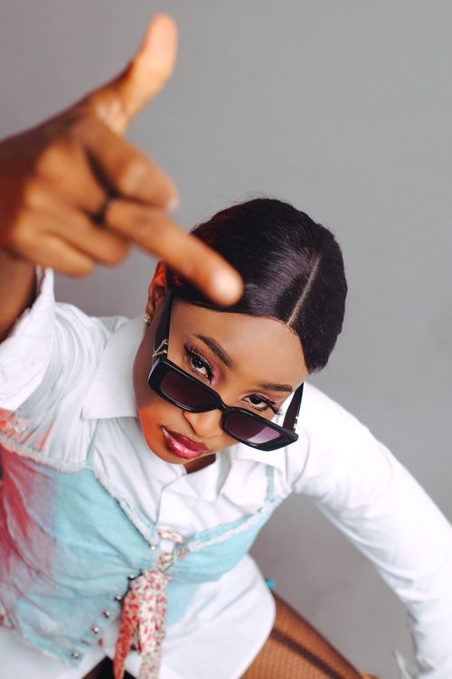 Free Stylish African woman making a bold gesture, wearing sunglasses indoors. Stock Photo
