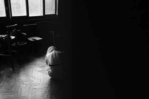 Free Dramatic black and white image of woman sitting indoors with dark tones and light contrast. Stock Photo