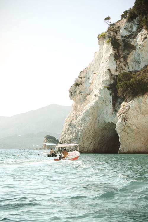 People on Motorboats near Rocks and Cave on Sea Shore