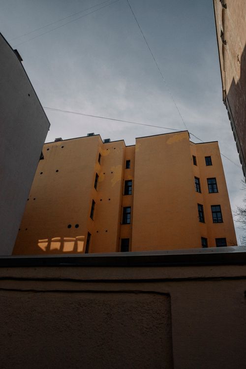 Free A modern building with a striking yellow facade and windows captured at an upward angle in an urban setting. Stock Photo
