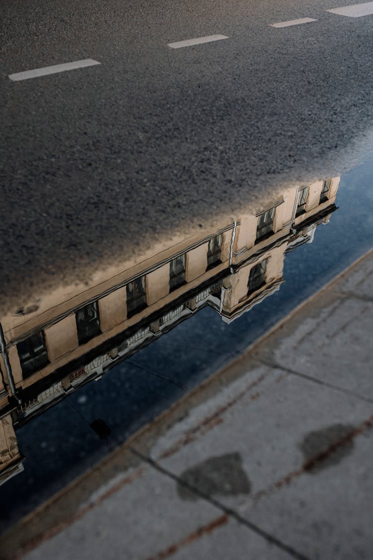 A Building Reflected In A Street Puddle