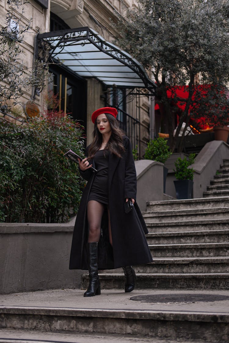 Fashionable Woman In A Black Coat And Red Beret Walking On Steps 