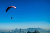 一架滑翔伞翱翔在风景如画的山脉上空，展现着自由与冒险