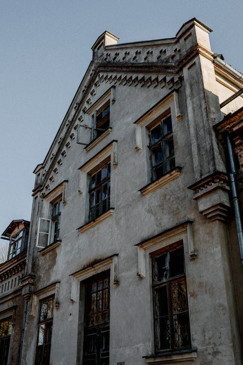 Free A vintage abandoned building facade with broken windows and architectural details. Stock Photo