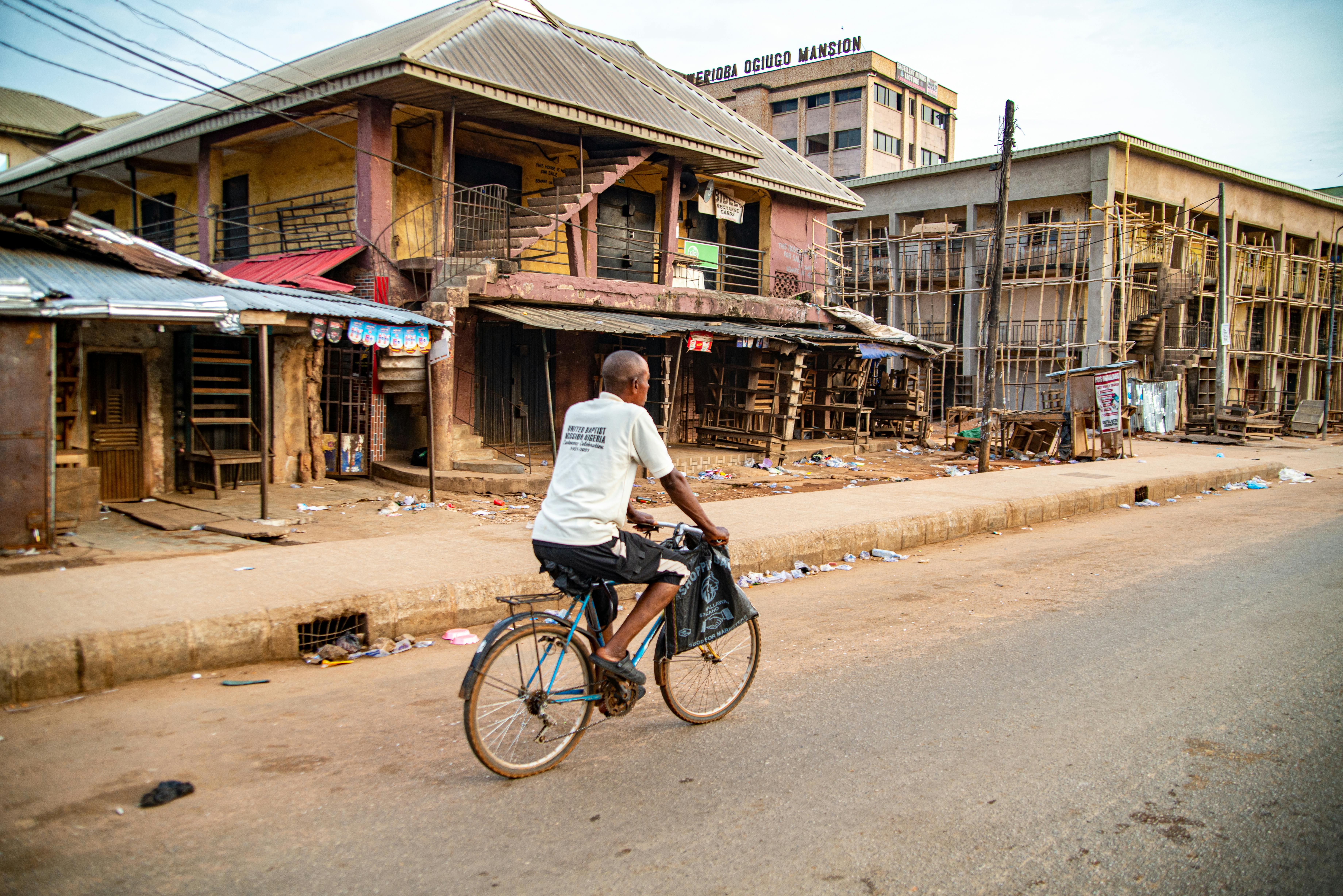 A cyclist rides along an empty street in an urban area of Nigel, South Africa, showcasing local architecture.