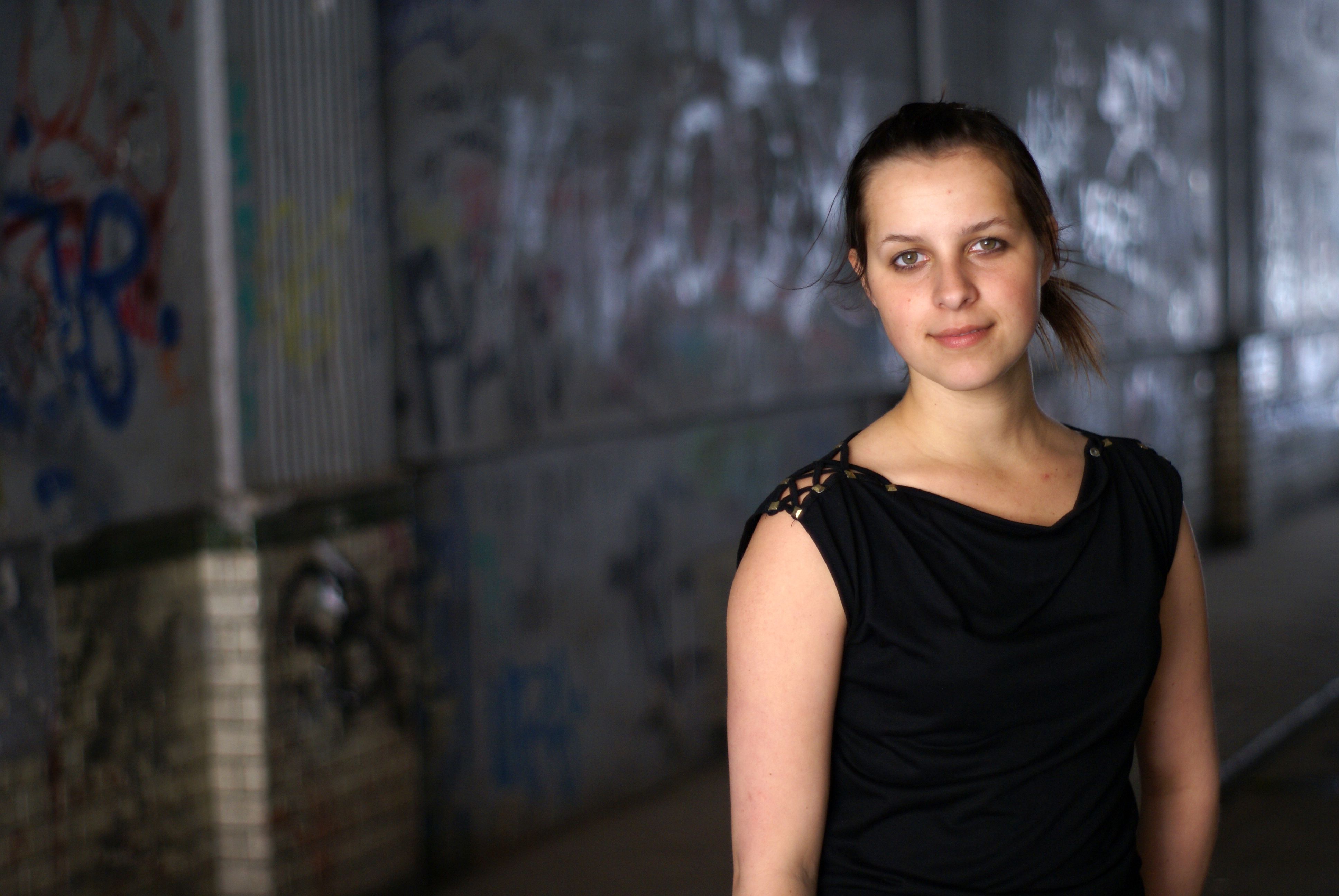 A woman in a black dress standing in front of a wall · Free Stock Photo