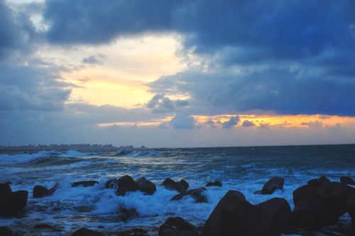 Free Dramatic sunset with crashing waves on rocky shore, capturing nature's beauty. Stock Photo