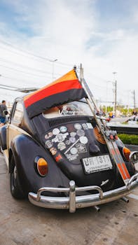 Classic VW Beetle showcasing nostalgia with a German flag and stickers at a car meetup.