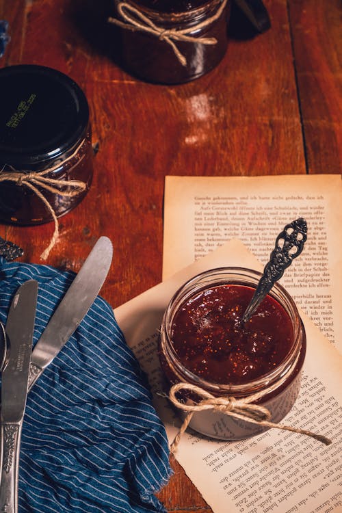 Free Jar of Strawberry Jam on Yellowed Pages Torn from a Book Stock Photo