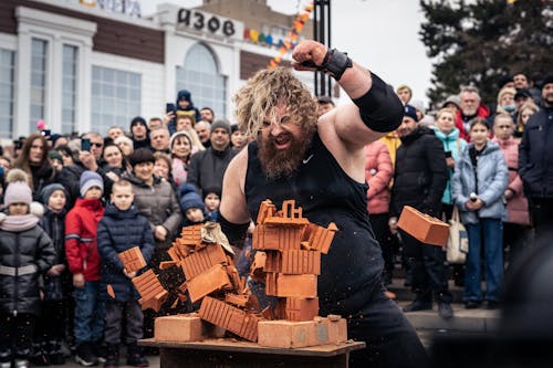 Crowd Watching a Man Break Bricks with His Arm 