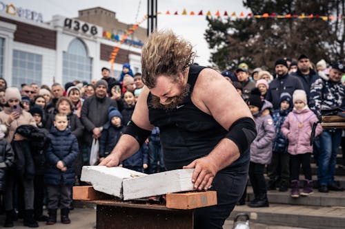 Crowd Watching a Man Break Bricks with His Arm 