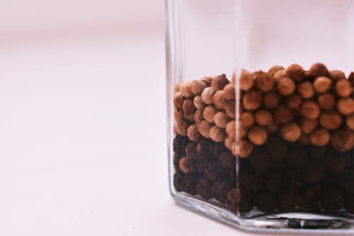 Selective Focus Photography of Peppercorns Inside Glass Container on White Surface
