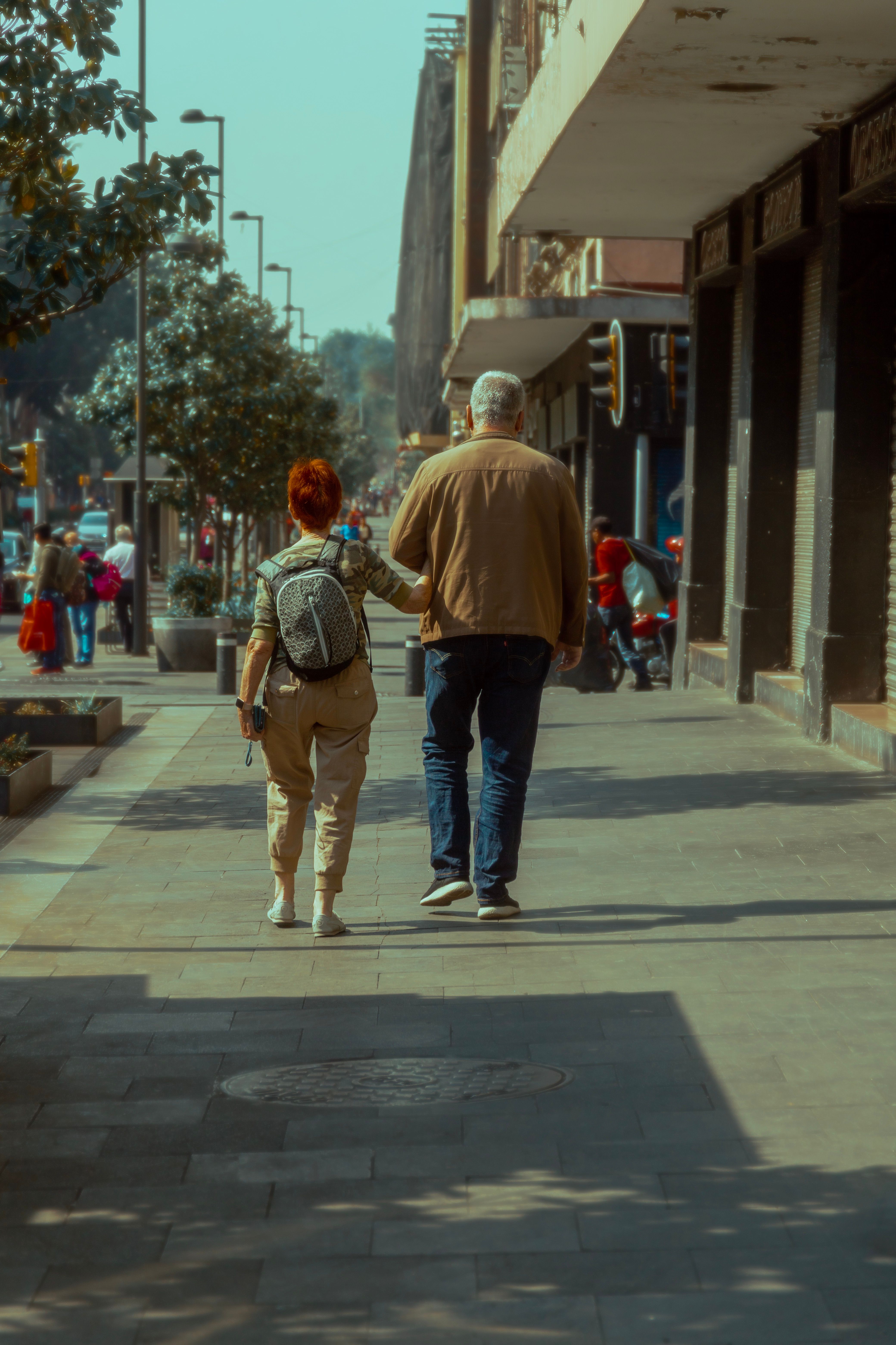 Fotomural Una pareja camina de brazo a brazo por una soleada calle urbana en la Ciudad de México, destacando un estilo de vida relajado.