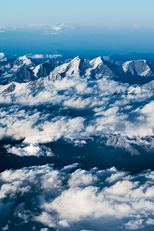 Free Stunning aerial view of snow-capped mountains with dramatic clouds underneath, showcasing breathtaking natural beauty. Stock Photo