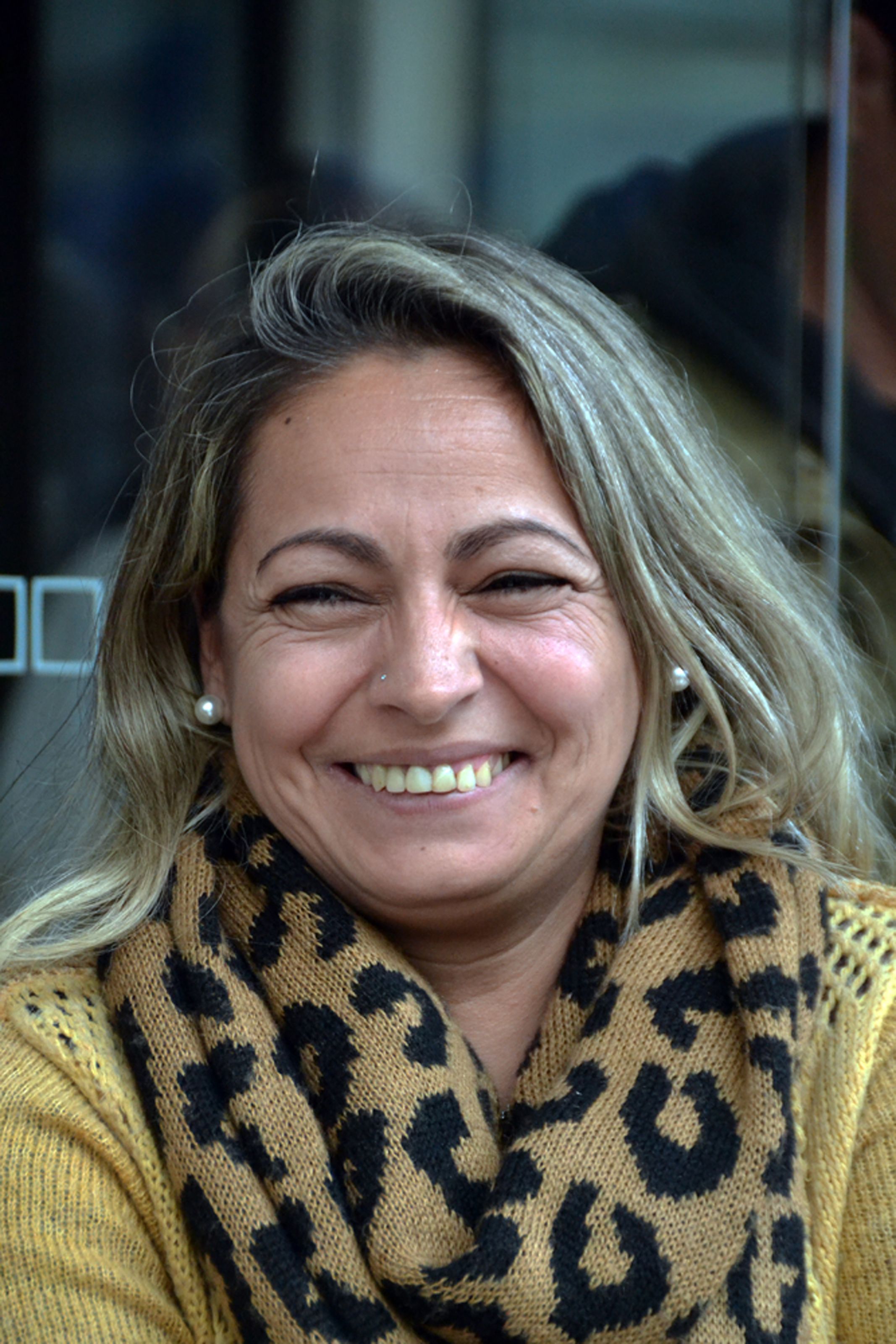 Cheerful woman with blonde hair wearing a leopard print scarf, smiling outdoors.