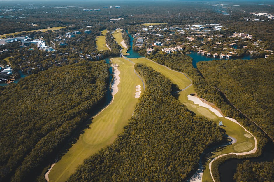 exclusive riviera maya experiences private - A breathtaking aerial shot of a lush golf course surrounded by dense forest in Playa del Carmen, Mexico.